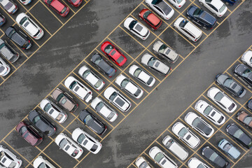 The open-air parking lot is neatly parked with many vehicles. Aerial top view