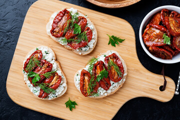 Bread slices with ricotta cheese and, sun dried tomatoes in olive oil. Top view