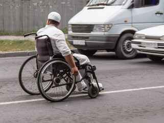 A man in a wheelchair asks for alms from the drivers of the main city highway.