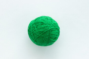 One round ball of green color in the center of the frame on a white woven background on the theme...