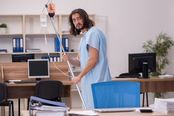 Young sick male employee in blood transfusion concept
