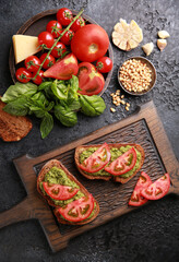 Italian cuisine. Recipe, cooking process. Serving bruschetta with pesto sauce, fresh tomatoes on a wooden board. Rustic. Ingredients. Background image, copy space. Top view