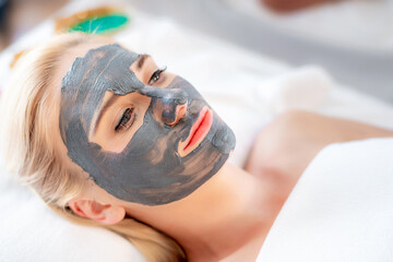 Beautiful young attractive Caucasian woman having clay mask or mud mask her face by Thai Masseur in spa salon. Beauty treatment and body care lifestyle concept	