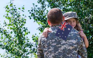 Reunion of soldier from Australia with family, daughter hug father. A girl holds the flag of...
