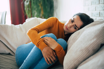Sad woman in deep depression is sitting on the couch and crying and thinking about the bad thing