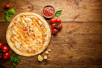 Tasty pizza with chicken and Sweet and sour sauce and cooking ingredients tomatoes and basil on wooden background. Top view