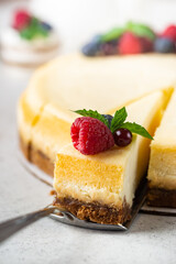 Classic New York cheesecake with fresh berries on white concrete background