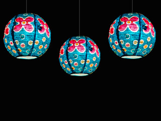 hanging paper lanterns on black background. interior decoration, colorful hanging lights.