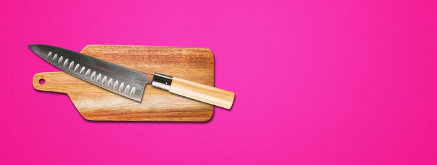 Traditional Japanese gyuto chief knife on a cutting board. Pink banner background