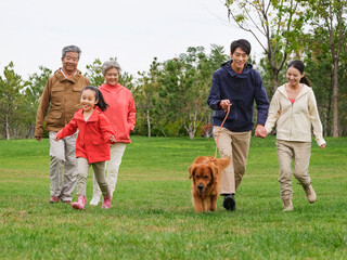 Obraz premium Happy family of five and pet dog walking in the park