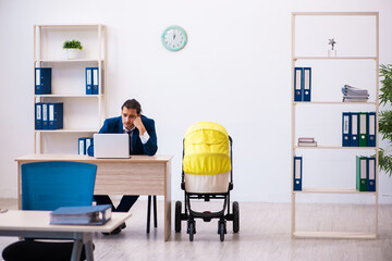 Young male employee looking after kid at workplace