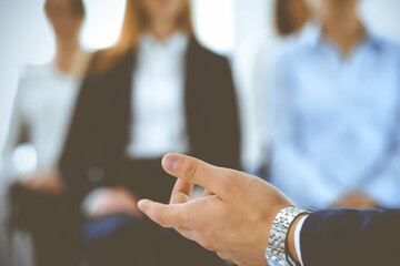 Obraz premium Business man making presentation to group of people, close-up. Speaker delivering a seminar to his colleagues or business training in office. Teamwork and coaching concept