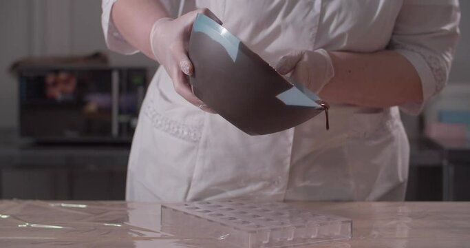 Pastry chef fills forms with chocolate. Chocolate candys production.
