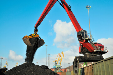 A manipulator crane in the seaport is used for unloading wagons and loading bulk cargo into the holds of sea ships.