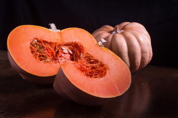 Whole fresh orange big pumpkin and slice of pumpkin on black background, closeup. Organic...