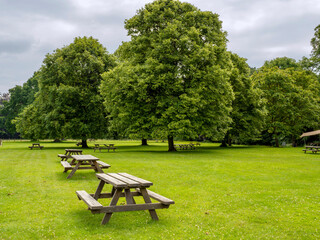 Wooden picnic tables in a field in a park