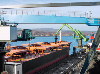 A manipulator crane in the seaport is used for unloading wagons and loading bulk cargo into the holds of sea ships.