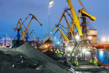Coal is loaded into the holds of a dry cargo ship in the seaport 24 hours a day.