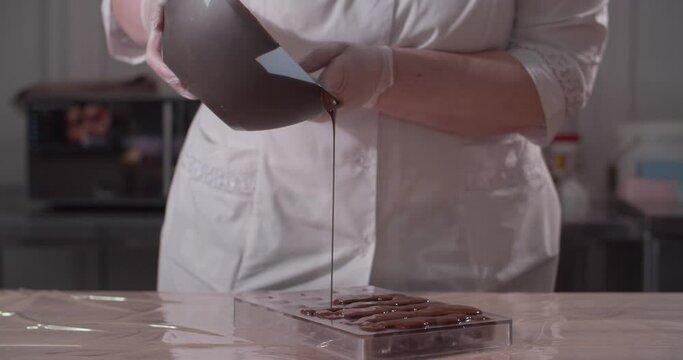 Pastry chef fills forms with chocolate. Chocolate candys production.