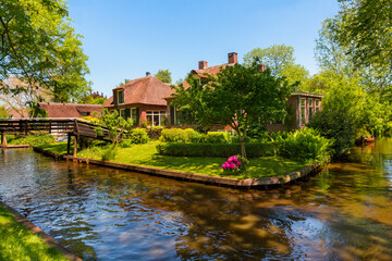 Fototapeta na wymiar The famous village of Giethoorn in the Netherlands with traditional dutch houses, gardens and water canals and wooden bridges is know as 