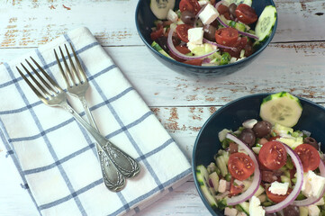 Greek salad of fresh juicy vegetables, feta cheese, herbs and olives in a blue bowl
