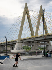 Fototapeta premium young man in black rollerskating in skate park near milllennium bridge in kazan city