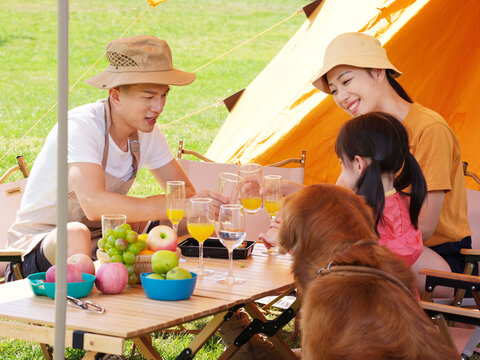 Happy family of three and pet dog have a picnic outdoors