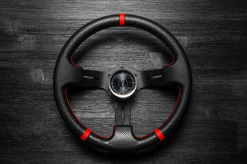 Car sport steering wheel on the black flat lay background. Motorsport.