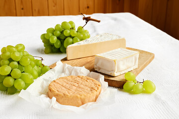 Delicious cheese brie or camembert, baguette and glass of wine on the table with white tablecloth. Dairy products. Italian, French cheese. Breakfast. - Powered by Adobe