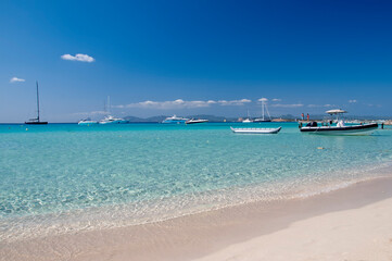 Ses Illetes Beach on the island of Formentera, Spain. In the background anchored boats and the blue sky