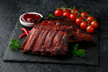 Grilled pork ribs with bbq sauce and herbs on stone board