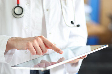 Doctor pressing his finger on touch screen of digital tablet in clinic concept