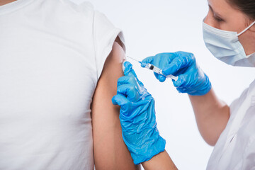 Girl doctor holds a syringe and makes an injection to a patient in a medical mask. Covid-19 or coronavirus vaccine. Masked man receiving coronavirus vaccination graft - obrazy, fototapety, plakaty