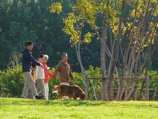Happy family of five and pet dog walking in the park