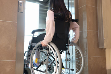 Disabled woman in wheelchair entering elevator back view © H_Ko