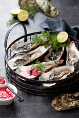 Open oysters with raspberry vinegar and shallots on a plate, selective focus