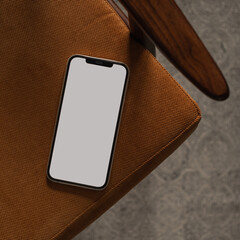 Flatlay of blank screen mobile phone on retro chair and carpet. Home office desk workspace. Lady,...