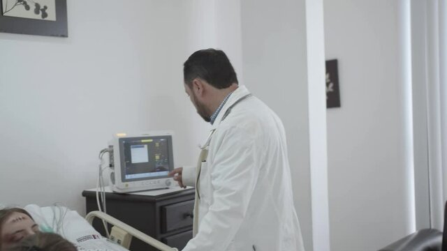 A male doctor nodding his head near a female patient monitoring her vital signs along side her mother, Slider Shot