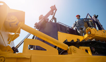 Industrial portrait of working man, excavator driver climbs into cab to perform work on...