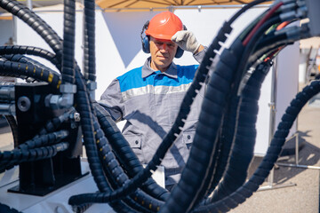 Worker man chek pipe system of hydraulic hose valves in industry machinery