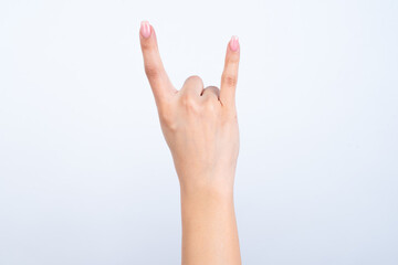 Woman's hand with pink manicure over isolated white background showing horns