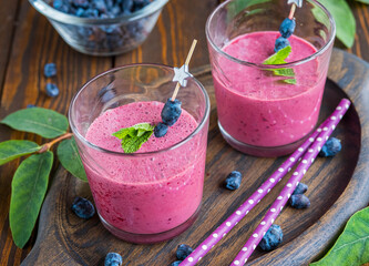 Smoothie or lassi, indian natural yogurt drink with honeysuckle in glasses on brown wooden...