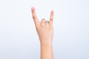Isolated woman's hand gesturing up with hand rock and roll, horn sign. Back side of the hand.