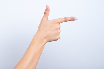 hands with a pink manicure pointing side with two fingers pretending to be a gun. 