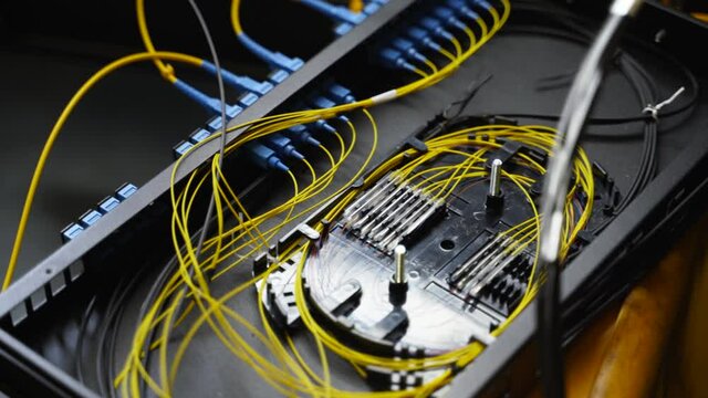 Worker connects optical line internet wire in connection box. Service man soldering optical fiber. Internet service provider engineer working in server room with the optic fiber and router wiring.