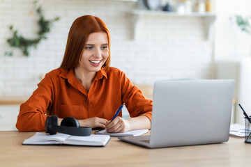 Online learning, portrait of beautiful red-haired young female student with laptop and notepad...