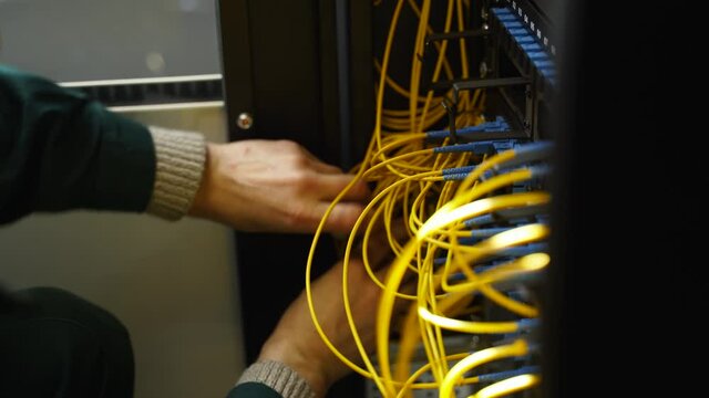 Worker connects optical line internet wire in connection box. Service man soldering optical fiber. Internet service provider engineer working in server room with the optic fiber and router wiring.