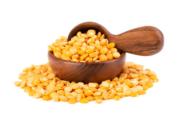 Dry yellow split peas in wooden bowl and spoon, isolated on white background. Halves of yellow legume peas.