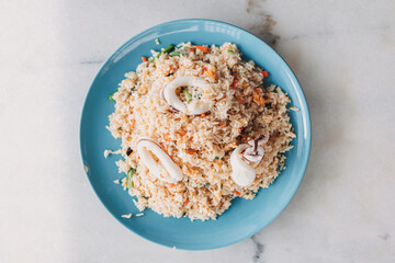 Thai style Squid Fried Rice served in blue ceramic dish on white table.
