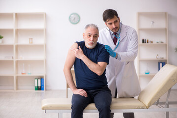 Obraz premium Old male patient visiting young male doctor in vaccination conce